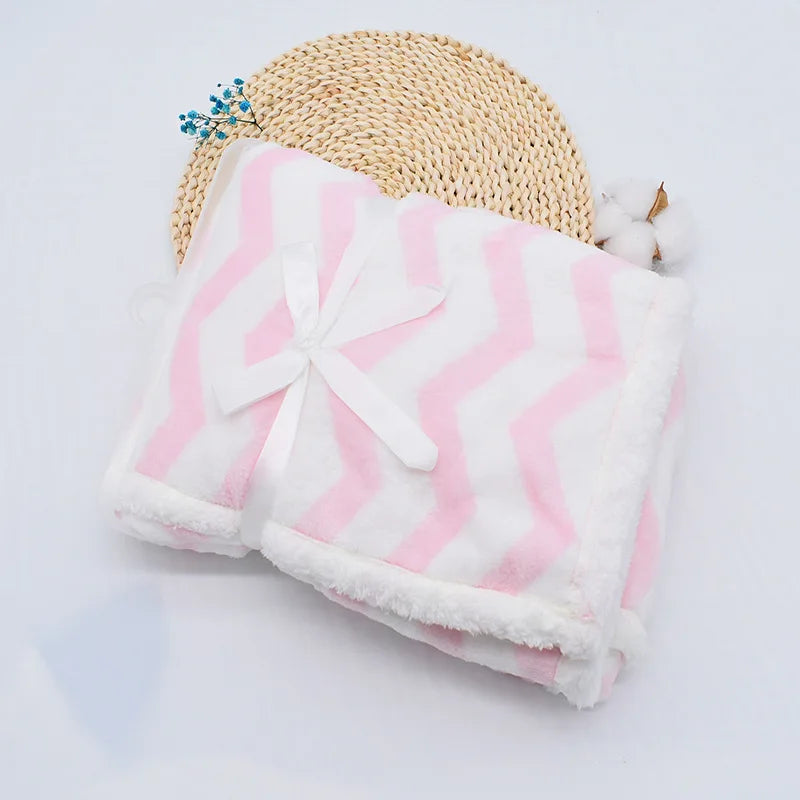 couverture bébé thermique pliée motifs lignes brisées rose blanc présenté sur naperon