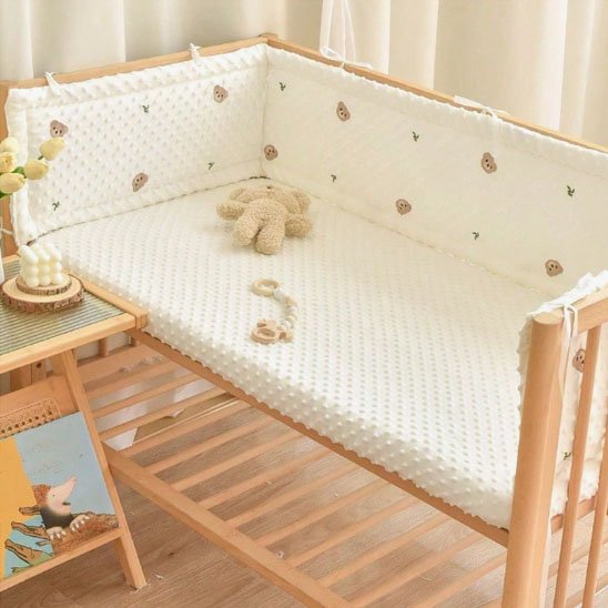tour de lit bébé tissu avec texture ourson fond blanc peluche dans lit