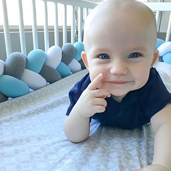 tresse de lit simple blanche bleue grise enfant souriant berceau blanc